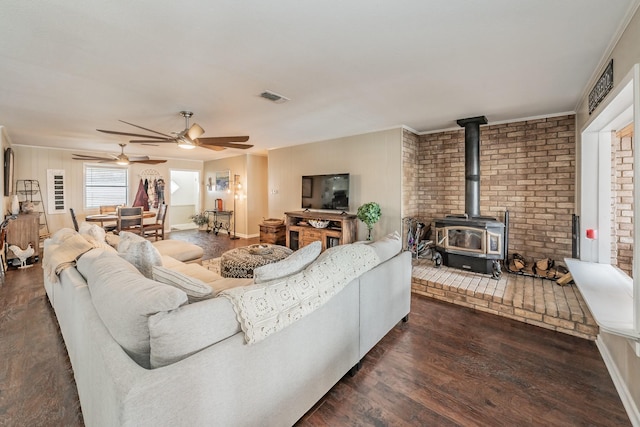 living area featuring a ceiling fan, visible vents, wood finished floors, and a wood stove
