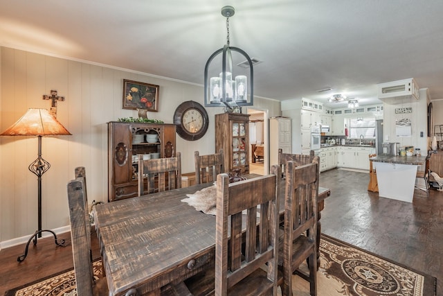 dining area with crown molding, an inviting chandelier, and dark wood-type flooring