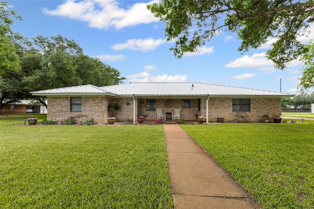 ranch-style house featuring metal roof, a front lawn, and brick siding