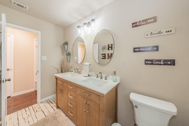 full bathroom with a sink, toilet, double vanity, and visible vents