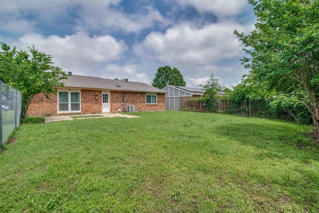 rear view of property featuring cooling unit, a patio, a fenced backyard, brick siding, and a lawn
