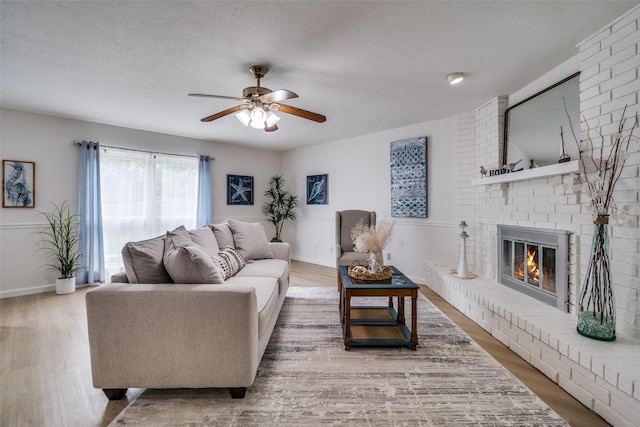 living room with baseboards, ceiling fan, wood finished floors, and a fireplace