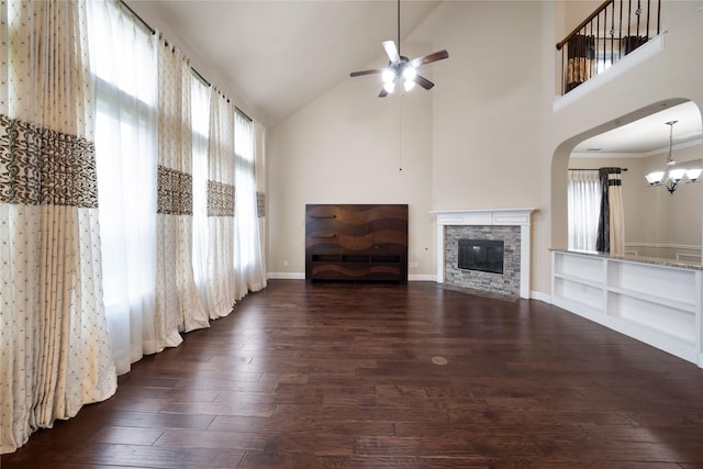 unfurnished living room featuring a stone fireplace, high vaulted ceiling, dark wood-style flooring, and ceiling fan with notable chandelier