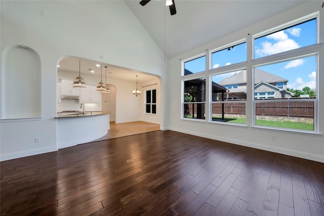 6917 Moody Ave, Frisco, TX 75035 - unfurnished living room with arched walkways, ceiling fan, a chandelier, hardwood / wood-style floors, and high vaulted ceiling