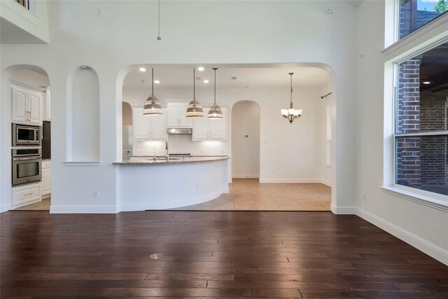 6917 Moody Ave, Frisco, TX 75035 - unfurnished living room featuring light wood-type flooring, arched walkways, a towering ceiling, recessed lighting, and a chandelier