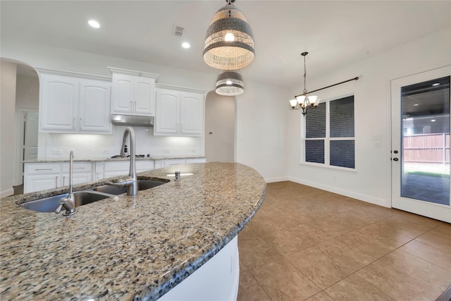 6917 Moody Ave, Frisco, TX 75035 - kitchen with arched walkways, white cabinetry, hanging light fixtures, light stone counters, and recessed lighting