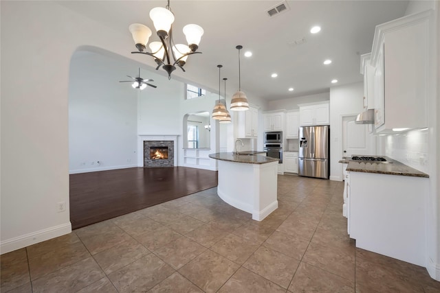 6917 Moody Ave, Frisco, TX 75035 - kitchen featuring stainless steel appliances, arched walkways, ceiling fan, a fireplace, and white cabinets