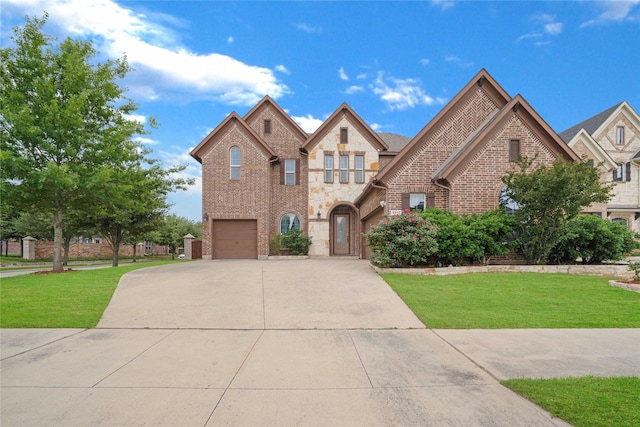 french country style house with concrete driveway, stone siding, a front lawn, and a garage