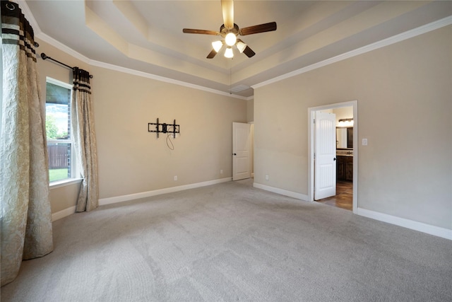 unfurnished bedroom featuring carpet flooring, crown molding, ensuite bathroom, baseboards, and a raised ceiling