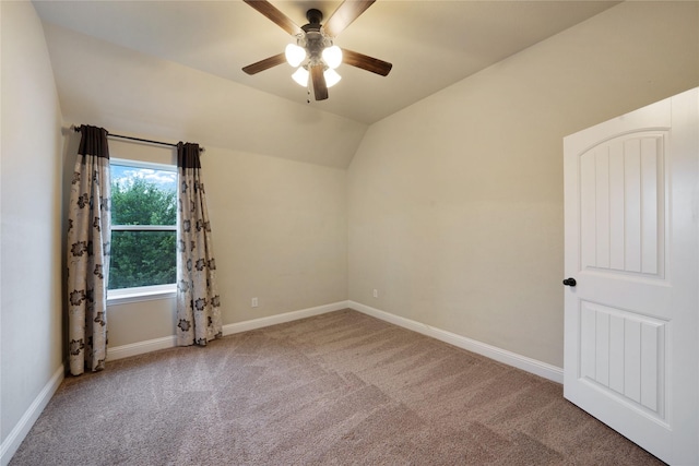 carpeted empty room featuring a ceiling fan, baseboards, and vaulted ceiling