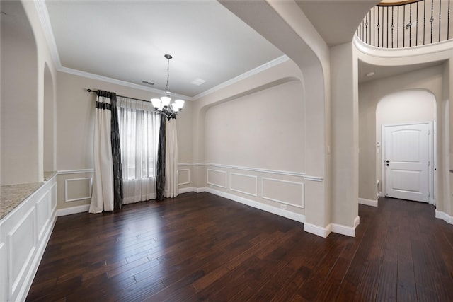 empty room with a chandelier, a decorative wall, visible vents, and dark wood-type flooring