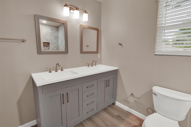 703 S Montgomery St, Sherman, TX 75090 - bathroom featuring toilet, wood finished floors, baseboards, and double vanity