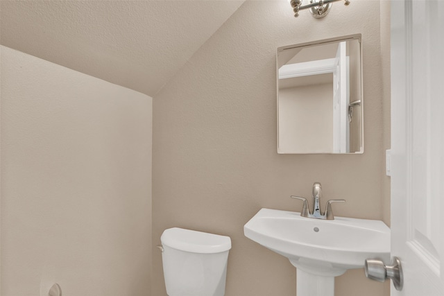 703 S Montgomery St, Sherman, TX 75090 - half bathroom with vaulted ceiling, a sink, and toilet