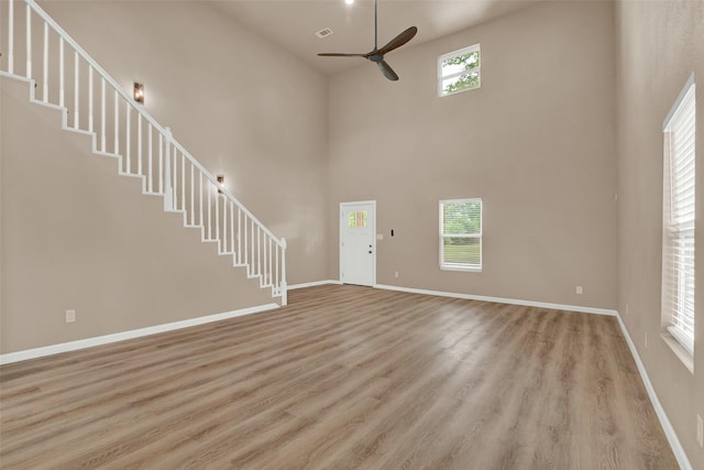 703 S Montgomery St, Sherman, TX 75090 - unfurnished living room featuring a ceiling fan, a towering ceiling, stairway, light wood-style flooring, and baseboards