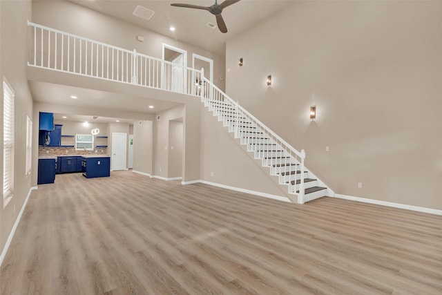 703 S Montgomery St, Sherman, TX 75090 - unfurnished living room featuring a towering ceiling, a ceiling fan, light wood-style floors, baseboards, and stairs