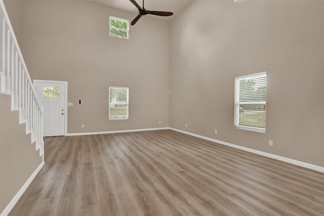 703 S Montgomery St, Sherman, TX 75090 - unfurnished living room with a towering ceiling, ceiling fan, stairs, baseboards, and light wood-style flooring