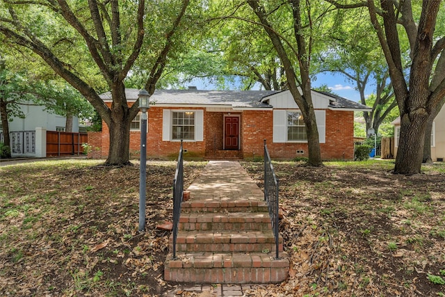 view of front of house with fence, roof with shingles, and brick siding