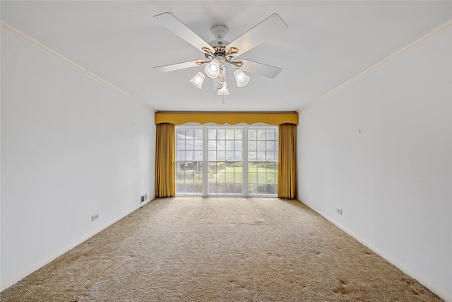 carpeted empty room featuring crown molding, ceiling fan, visible vents, and baseboards