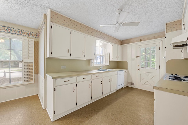 kitchen featuring a textured ceiling, visible vents, a sink, white appliances, and a wealth of natural light