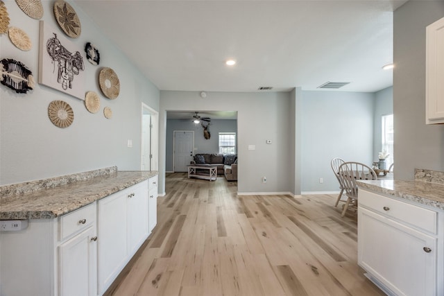 kitchen featuring white cabinets, visible vents, and light wood-style floors