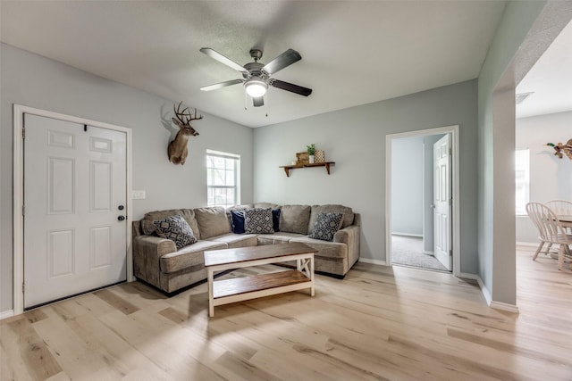 living area featuring light wood-style floors, baseboards, a ceiling fan, and visible vents