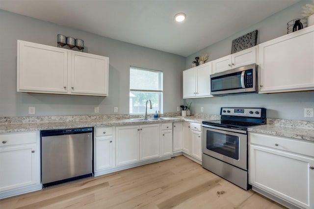 kitchen with light countertops, light wood-style flooring, appliances with stainless steel finishes, and white cabinets