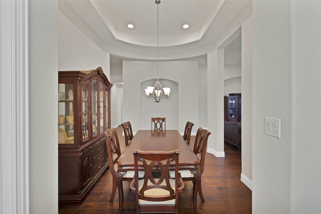 dining area featuring dark wood-style flooring, a raised ceiling, baseboards, a notable chandelier, and recessed lighting