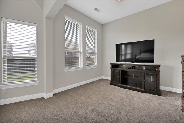 unfurnished living room with carpet flooring, baseboards, visible vents, and plenty of natural light