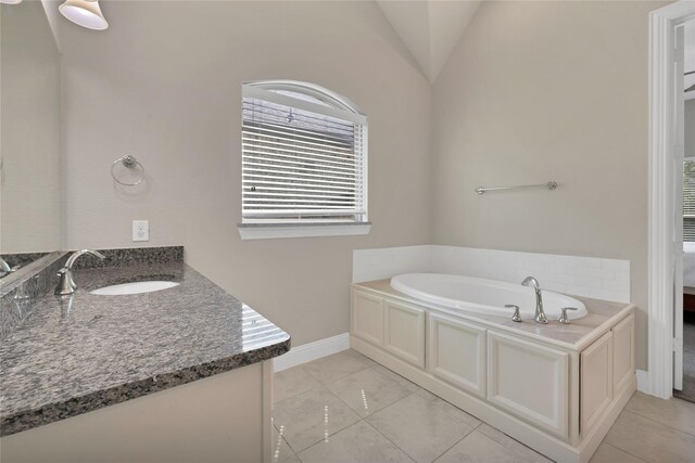 full bathroom featuring baseboards, a bath, vaulted ceiling, and vanity