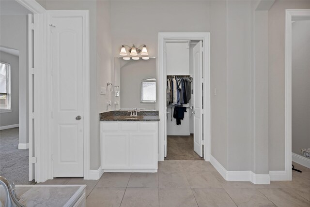 bathroom featuring an inviting chandelier, baseboards, plenty of natural light, and vanity