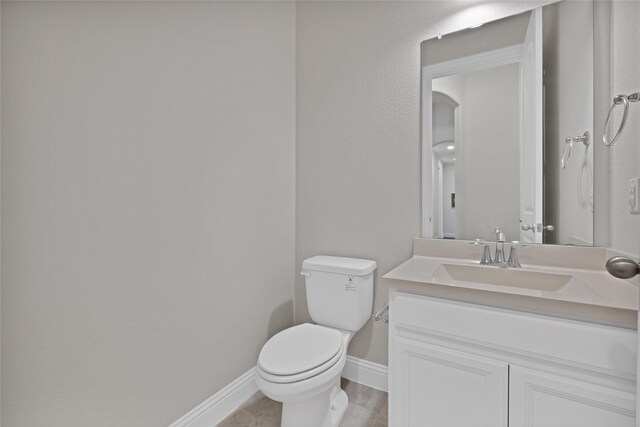 bathroom featuring baseboards, vanity, and toilet