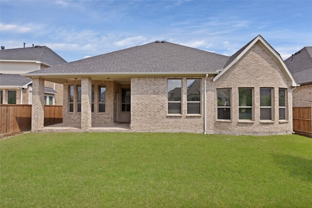 back of property featuring brick siding, a fenced backyard, roof with shingles, and a lawn