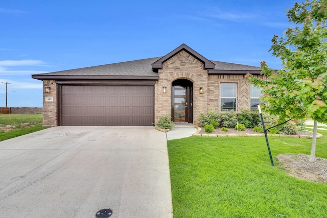 french country style house featuring brick siding, a front lawn, an attached garage, and concrete driveway