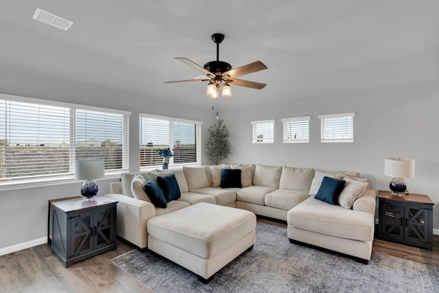 living area with baseboards, a ceiling fan, wood finished floors, and visible vents
