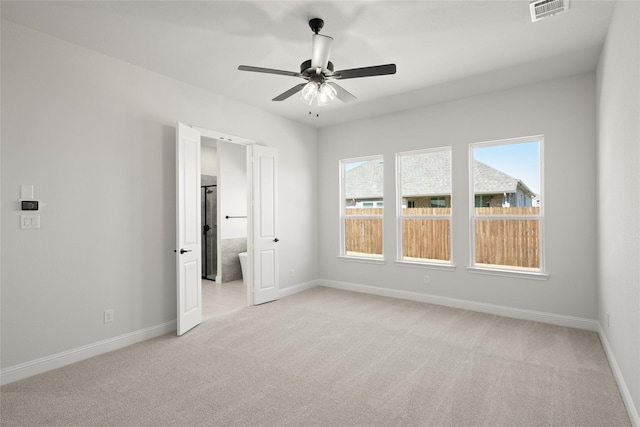 unfurnished bedroom featuring visible vents, connected bathroom, baseboards, and light colored carpet