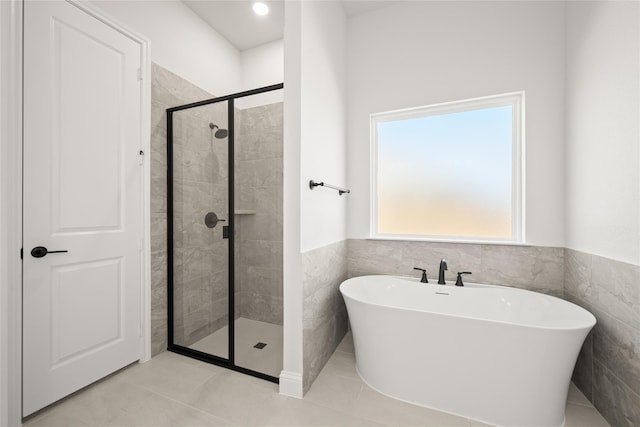 full bath featuring tile patterned floors, a stall shower, tile walls, and a soaking tub
