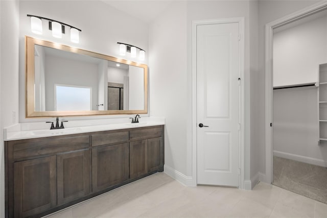 full bathroom featuring double vanity, a sink, baseboards, a spacious closet, and a shower with door