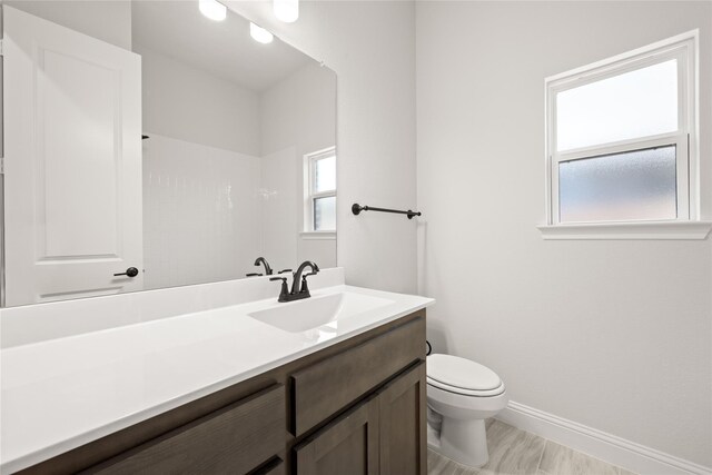bathroom with baseboards, toilet, and vanity