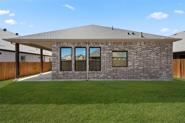 back of property featuring fence, a patio, brick siding, a shingled roof, and a yard