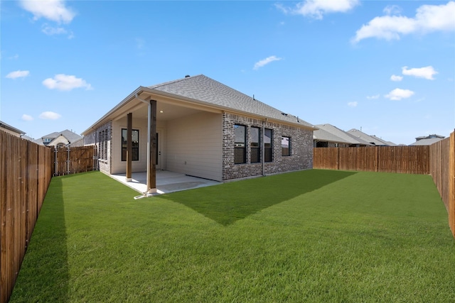 back of house featuring a lawn, brick siding, a fenced backyard, and a patio area
