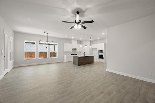 unfurnished living room with recessed lighting, baseboards, light wood-style flooring, and ceiling fan with notable chandelier