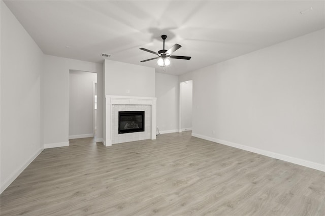 unfurnished living room with visible vents, baseboards, ceiling fan, a tiled fireplace, and light wood finished floors