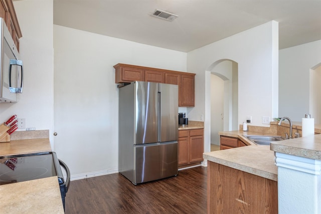 735 Cedar Cove Dr, Princeton, TX 75407 - kitchen featuring appliances with stainless steel finishes, a sink, arched walkways, dark wood-style flooring, and light countertops