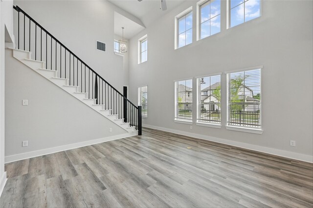 1000 Tulip Pl, Crowley, TX 76036 - unfurnished living room with a towering ceiling, ceiling fan, stairs, wood finished floors, and baseboards