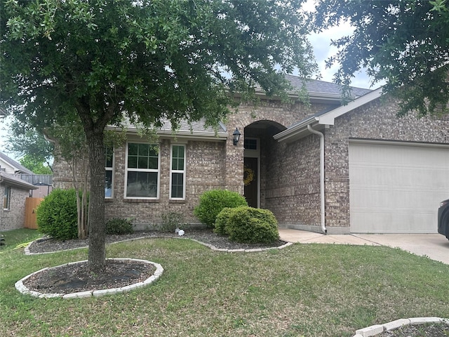 ranch-style home featuring brick siding, an attached garage, driveway, and a front lawn