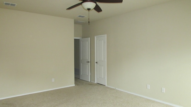 spare room featuring a ceiling fan, baseboards, light colored carpet, and visible vents