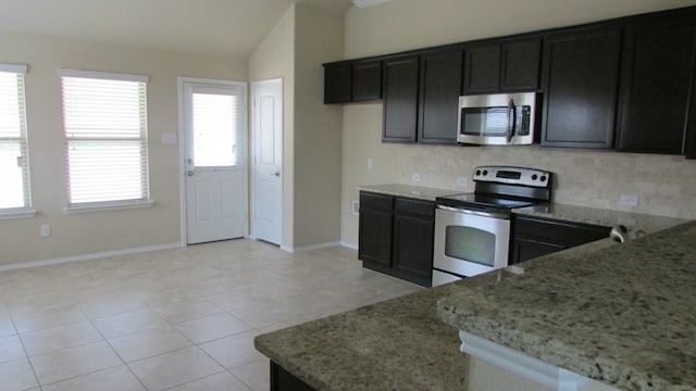 kitchen with light stone counters, appliances with stainless steel finishes, vaulted ceiling, and tasteful backsplash