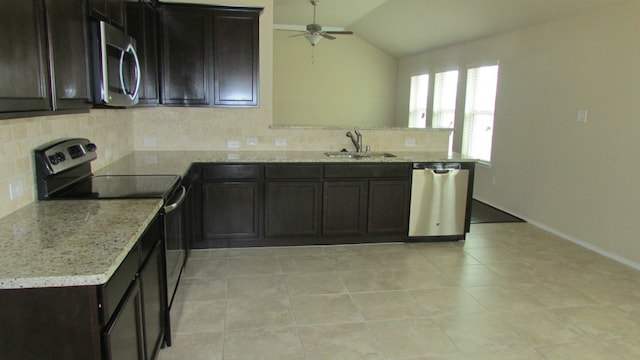 kitchen with ceiling fan, a sink, stainless steel appliances, decorative backsplash, and vaulted ceiling