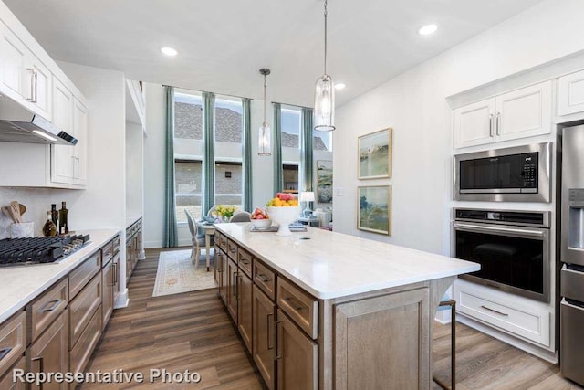 kitchen with a center island, dark wood-style flooring, appliances with stainless steel finishes, and under cabinet range hood