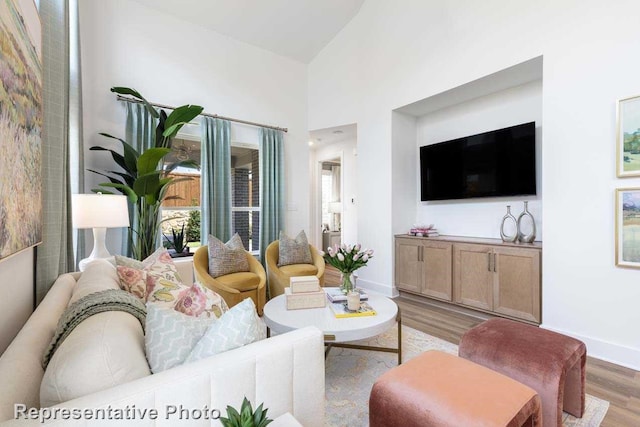 living room featuring baseboards, light wood-style flooring, and high vaulted ceiling